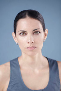 A woman in a grey shirt sits in front of a grey background