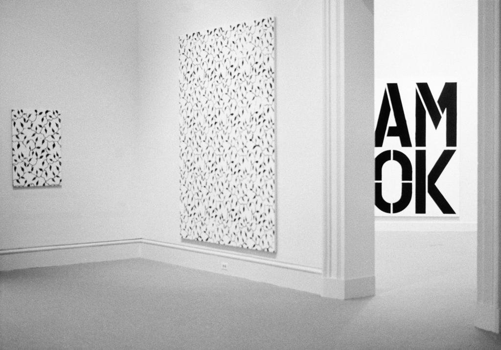 Black and white painting featuring a vine-like pattern and letters